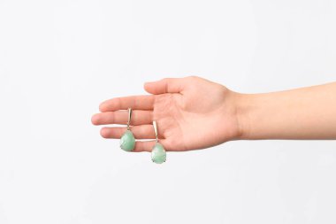 Beyaz arka planda güzel küpeleri olan bir kadın eli.