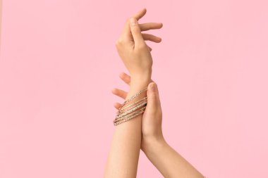 Pembe arka planda güzel bilezikleri olan kadın elleri.