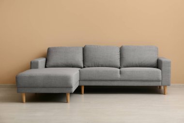 Oturma odasındaki bej duvarın yanındaki rahat kanepe.