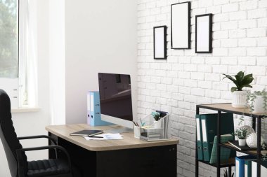 Çalışma yeri, koltuğu, modern bilgisayarı ve raf ünitesi olan ışık ofisinin içi