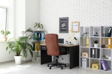 Çalışma odası, kahverengi koltuk, modern dizüstü bilgisayar ve raf ünitesi.