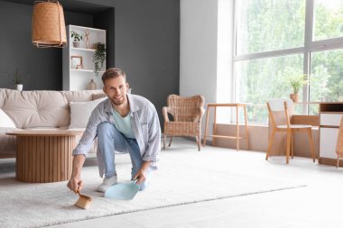 Işık odasında, toz tavası ve fırça temizliği yapan erkek hademe.