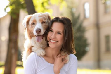 Parkta şirin bir çoban köpeği olan mutlu bir genç kadın.