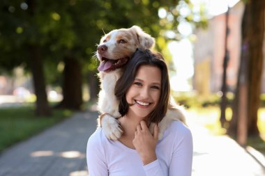 Parkta şirin bir çoban köpeği olan mutlu bir genç kadın.