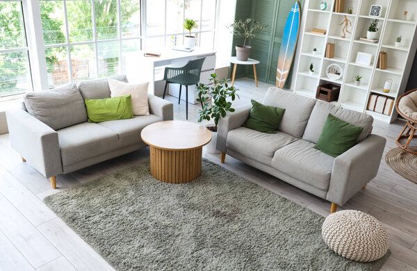 Interior of stylish modern living room with surfboard and sofas