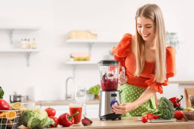 Genç bir kadın mutfakta blender ile pancar suyu yapıyor.