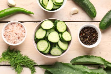 Taze salatalık ve ahşap arka planda baharat dolu kaseler.