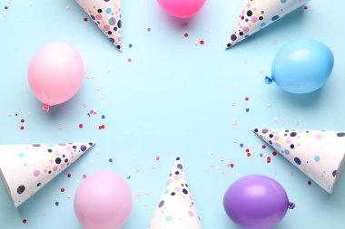 Soluk mavi arka planda parti şapkaları ve balonlardan yapılmış çerçeve