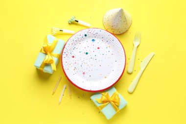 Sarı arka planda farklı parti dekorasyonu olan tek kullanımlık kağıt tabak.