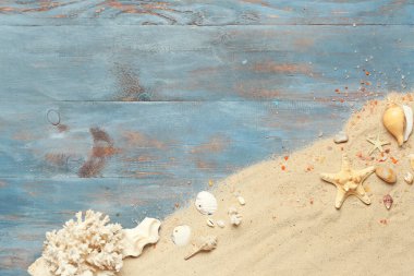 Mavi ahşap arka planda deniz yıldızı, deniz kabuğu ve mercan kumları