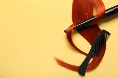 Sarı arka planda kızıl saç teli, tarak ve saç maşası