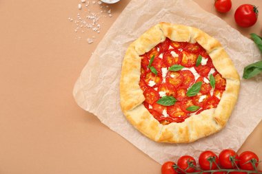 Lezzetli domates galeti ve bej arka planda fesleğen içeren kağıt fırını.