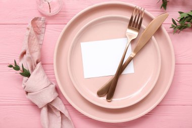 Boş kartlı şık masa ayarları ve pembe ahşap arka planda dallar.