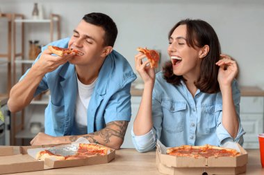 Genç bir çift mutfakta lezzetli biberli pizza yiyor.