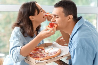 Genç bir çift mutfakta lezzetli biberli pizza yiyor.