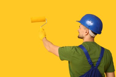 Erkek ressamın portresi sarı arka planda yuvarlak bir şey çiziyor.