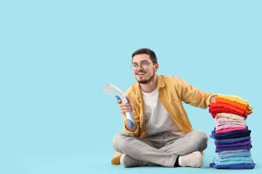 Mavi arka planda oturan temiz elbiseli ve modern buharlı mutlu genç adam.