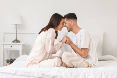 Mutlu genç çift yatak odasında burunlarına dokunuyor.