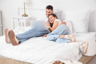 Yatak odasında dizüstü bilgisayar ile genç Çift