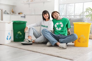 Mutfakta çöp konteynırları olan genç bir çift. Geri dönüşüm kavramı