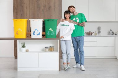 Mutfakta çöp konteynırları olan genç bir çift. Geri dönüşüm kavramı