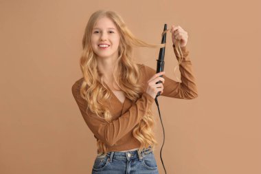 Kahverengi arka planda saç maşası olan güzel, mutlu bir kadın.