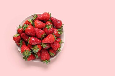 Pembe arka planda taze çilekli bir tabak.