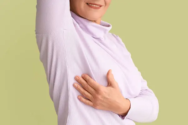 stock image Mature woman checking her breast on green background, closeup. Cancer awareness concept