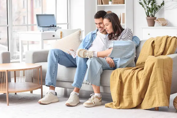 Mutlu genç çift evde dergi okuyor.