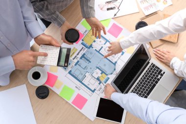 İş adamları ofis masasında ev planı üzerinde çalışıyorlar.