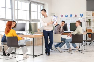 Trafik işaretleri olan erkek eğitmen sürücü okulundaki insanlara ders veriyor.