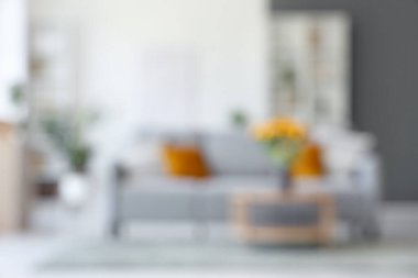 Oturma odası, kanepe, masa ve vazoda suni ayçiçekleri.