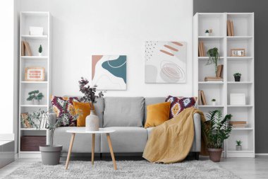 Oturma odasının içinde kanepe, masa ve vazoda yapay okaliptüs var.