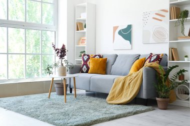 Oturma odasının içinde kanepe, masa ve vazoda yapay okaliptüs var.