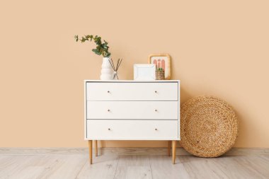 Yapay okaliptüslü vazo ve odada bej duvarın yanındaki klozette çerçeveler.