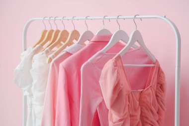 Pembe duvarın yanında asılı giysiler var.