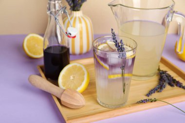 Çiçekli taze lavantalı limonata ve renkli arka planda ahşap sıkacağı.