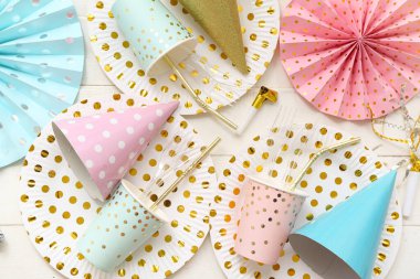 Hafif ahşap zemin üzerinde doğum günü partisi için kağıt tek kullanımlık sofra takımı ve dekor içeren kompozisyon