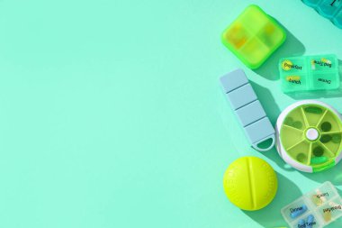 Turkuaz arka planda hapları olan farklı plastik kaplar. Üst görünüm