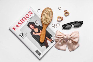 Dergi, saç fırçası ve arka planda şık kadın aksesuarları olan kompozisyon