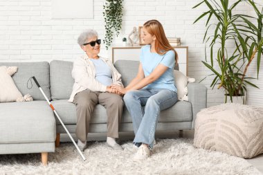 Evde kanepede oturan kör büyükannesi olan genç bir kadın.