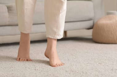Çıplak ayaklı kadın evdeki yumuşak halıda yürüyor, yakın plan.