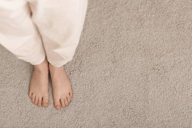 Evdeki yumuşak halıda çıplak ayaklı kadın.