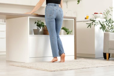 Mutfaktaki yumuşak halıda çıplak ayaklı kadın.