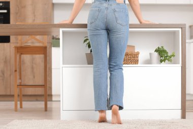 Mutfaktaki yumuşak halıda çıplak ayaklı kadın.