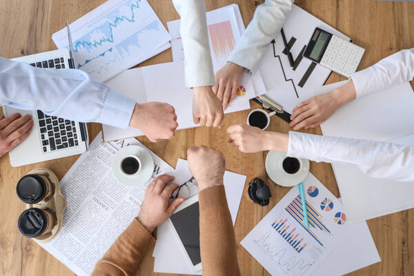 Business people bumping fists at table in office, top view