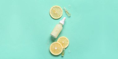 Turkuaz arka planda limon dilimleri olan C vitamini şişesi ve ampule.