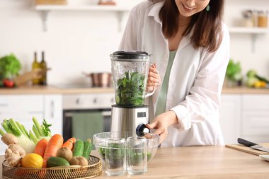 Mutfakta blender ile sebze suyu yapan genç bir kadın, yakın plan.