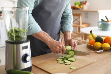 Mutfakta salatalık kesen olgun bir adam, yakın plan.