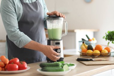 Olgun adam mutfakta blender ile smoothie yapıyor, yakın plan.